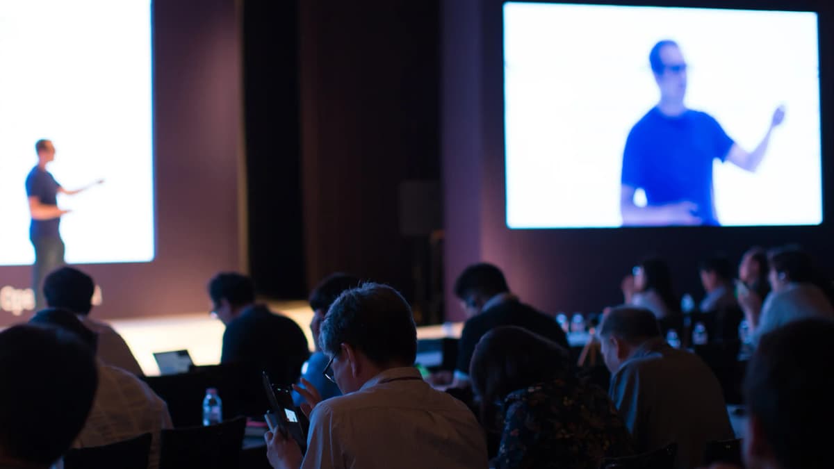 Conference attendees watching presenter give presentation.