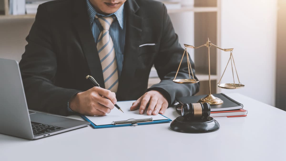 Male attorney sitting at desk holding pen.